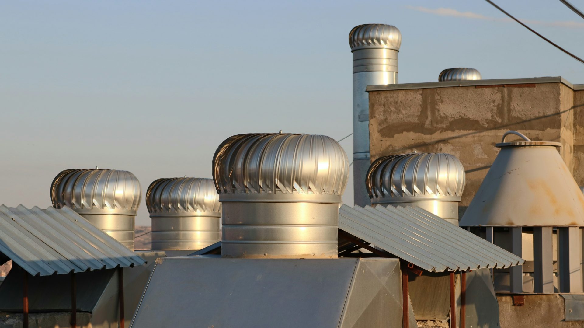 a row of metal chimneys on top of a building